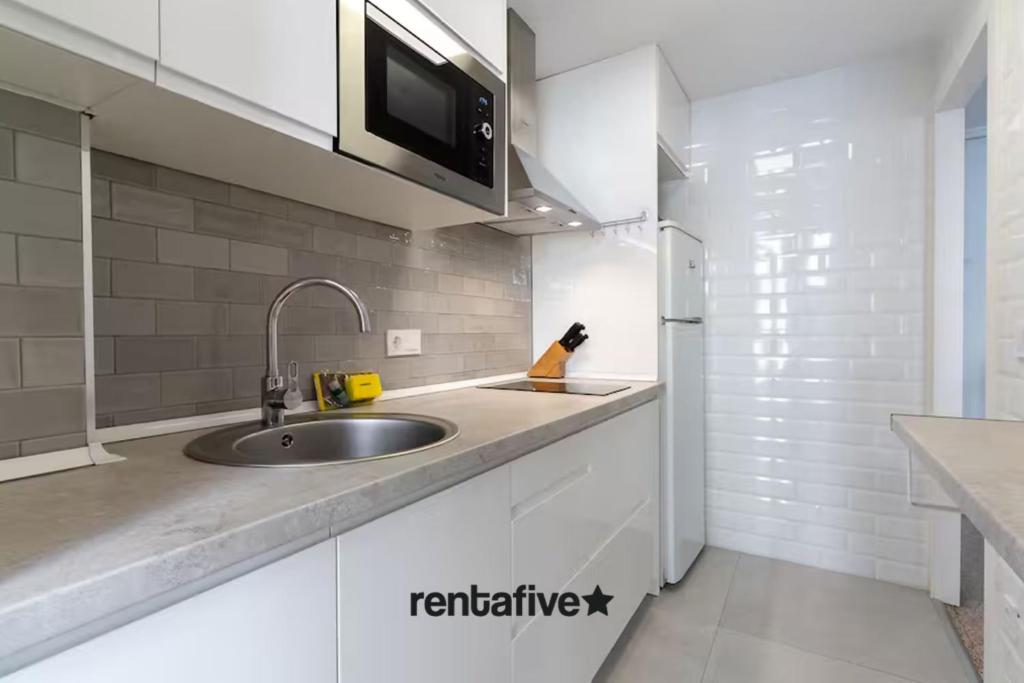 a white kitchen with a sink and a refrigerator at rentafive - Nuevo - Centro - A/C in Santa Pola