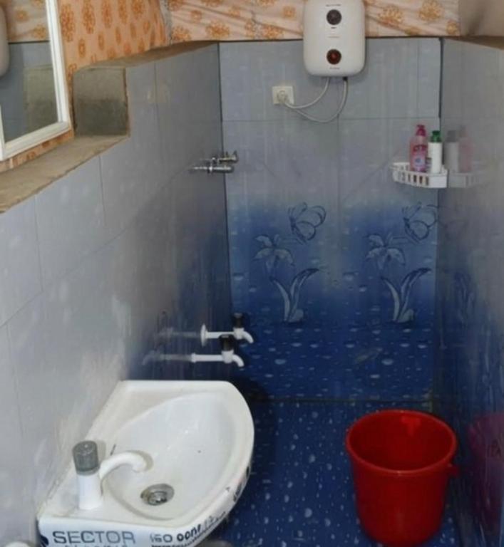 a bathroom with a sink and a red bucket at Araku Mountview Camping Resort in Araku