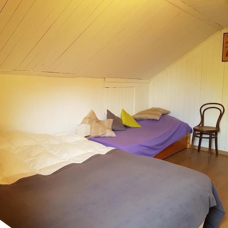 a bedroom with two beds and a chair at Le Vieux Logis 2 in La Celle-sous-Gouzon