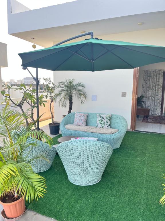 a patio with two chairs and a couch under an umbrella at Flora A suite in Jaipur