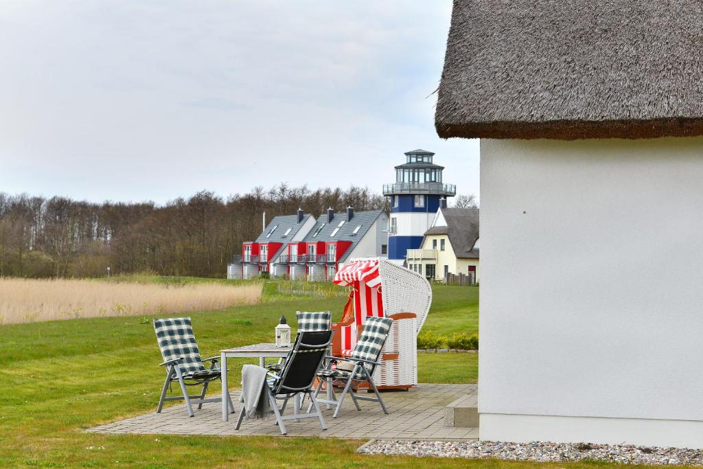 eine Gruppe Stühle und ein Tisch mit einem Leuchtturm im Hintergrund in der Unterkunft Ferienhaus Boddenblick in Breege