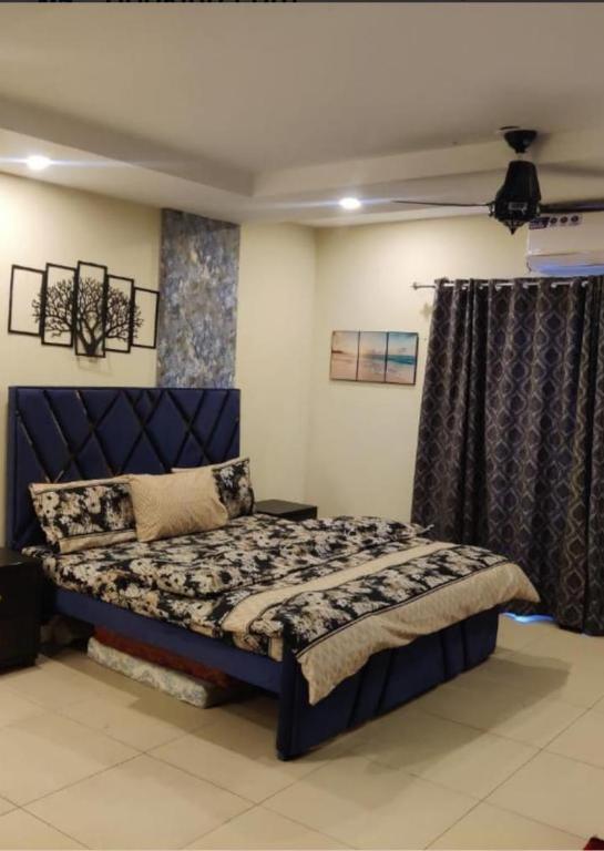 ein Schlafzimmer mit einem blauen Bett in einem Zimmer in der Unterkunft Suites Inn in Faisalabad