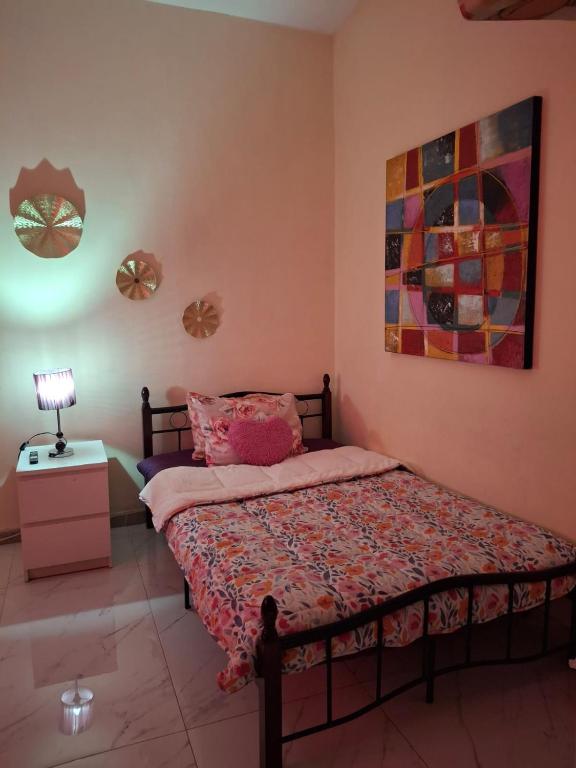 a bedroom with a bed and a lamp and a painting at Cozy Corner 2024 in Abu Dhabi