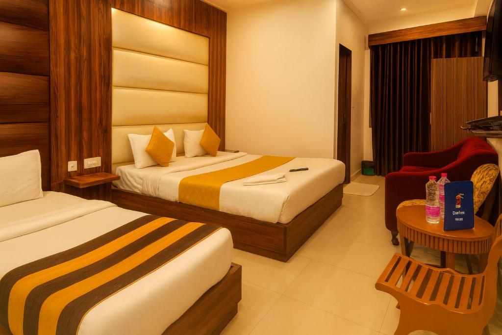 ein Hotelzimmer mit zwei Betten und einem Stuhl in der Unterkunft Hotel Earth By Aashiyana in Neu-Delhi