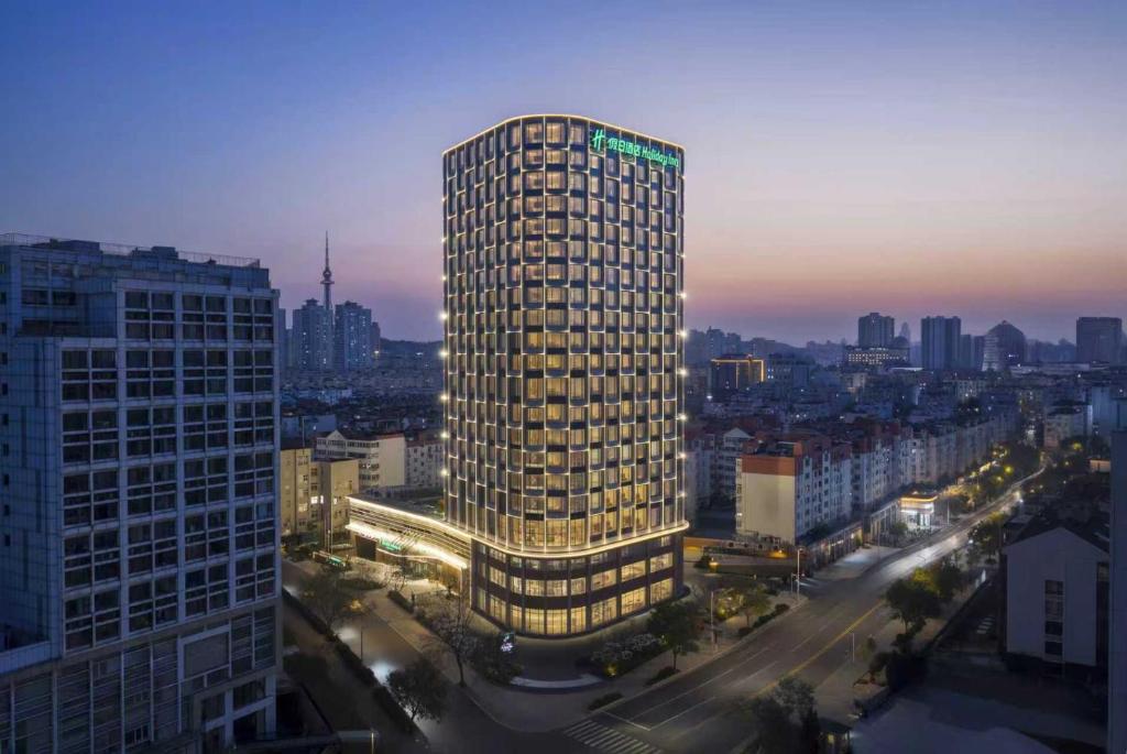 a tall building in a city at night at Holiday Inn Qingdao CBD by IHG in Qingdao