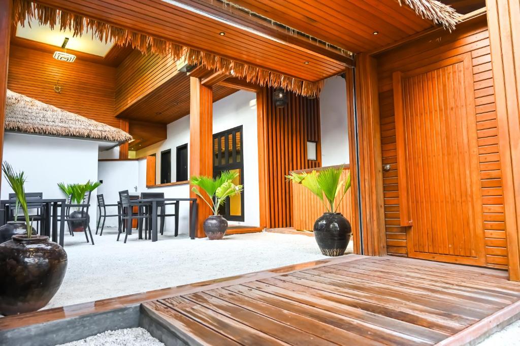 un patio aperto con pareti in legno, tavoli e piante di Oak Villa, Ukulhas a Ukulhas