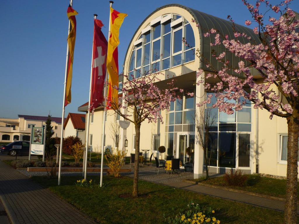 un bâtiment avec drapeaux devant lui dans l'établissement Hotel SunParc - SHUTTLE zum Europa-Park Rust 4km & Rulantica 2km, à Ringsheim