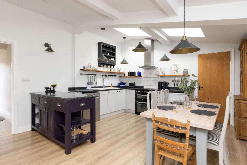 a kitchen with a table and a kitchen with white cabinets at Sidlesham Hideaway Logburner & Garden in Donnington