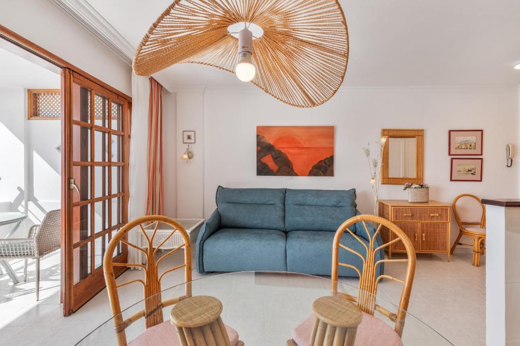 ein Wohnzimmer mit einem blauen Sofa und Stühlen in der Unterkunft Playa Delphin 106 in Puerto Naos