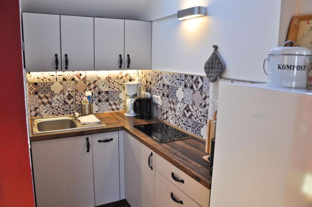 een kleine keuken met witte kasten en een spoelbak bij Ferienwohnung Wandersruh in Braunsberg