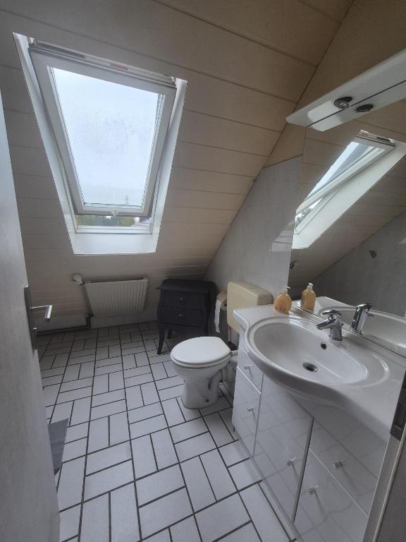 een badkamer met een wastafel en een toilet en een raam bij Süder11 - ApartD in Eddelak