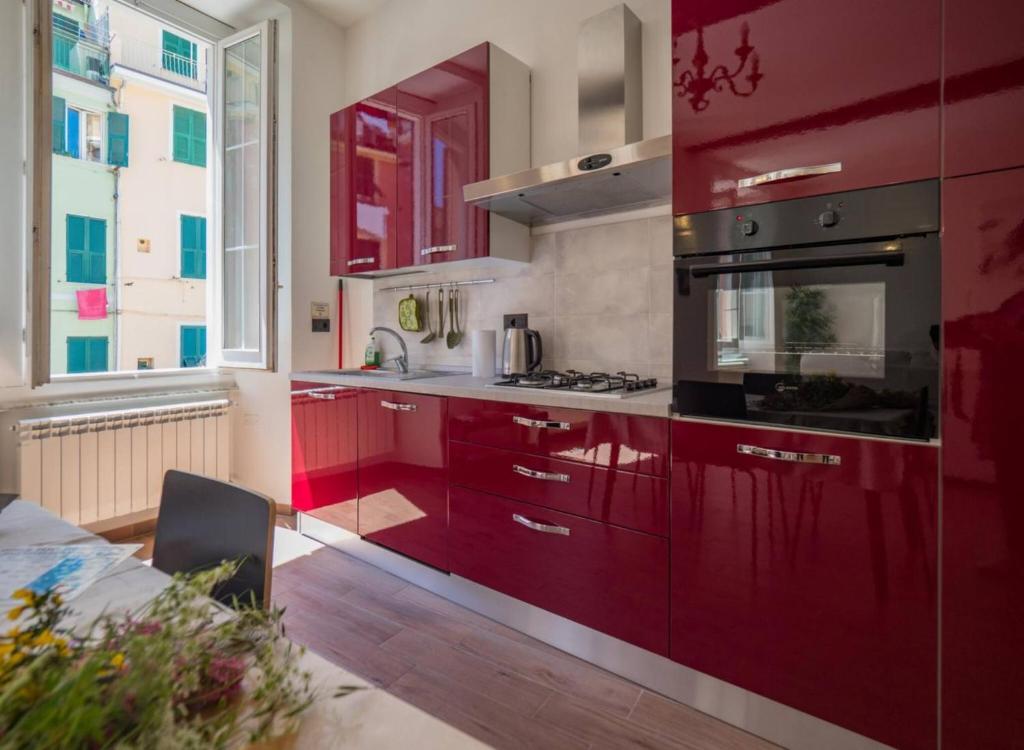 een keuken met rode kasten en een groot raam bij Tedea 2-bedroom 2-bathroom Exclusive Apartment in Vernazza