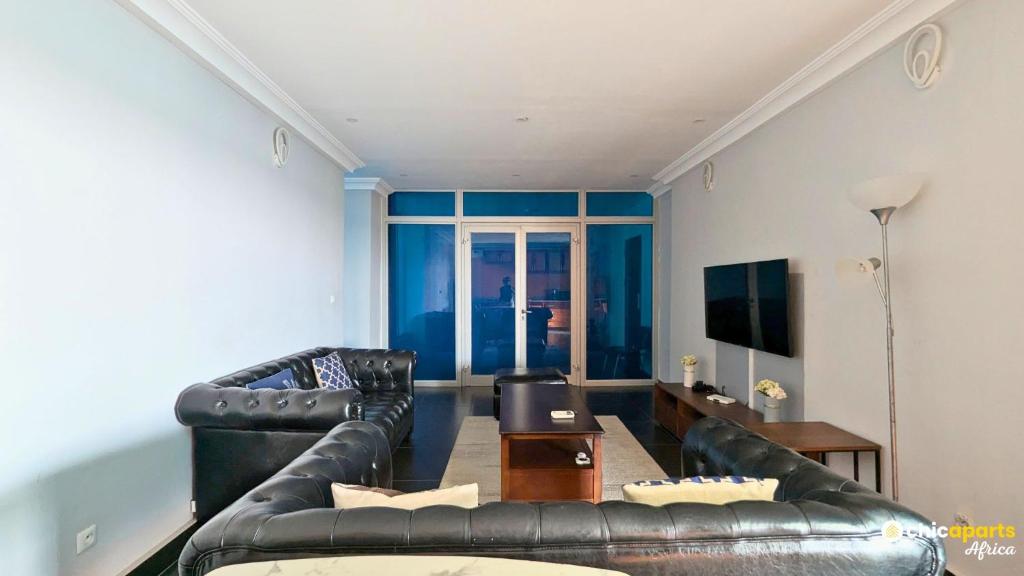 ein Wohnzimmer mit 2 Ledersofas und einem TV in der Unterkunft Chic studio with parking and pool in Douala