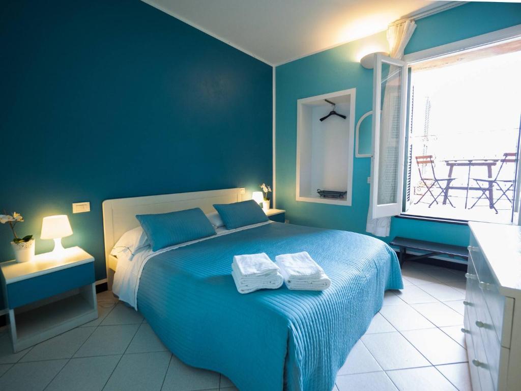 een blauwe slaapkamer met een bed met twee handdoeken erop bij Ventegà Sea View Apartment with Balcony in Vernazza