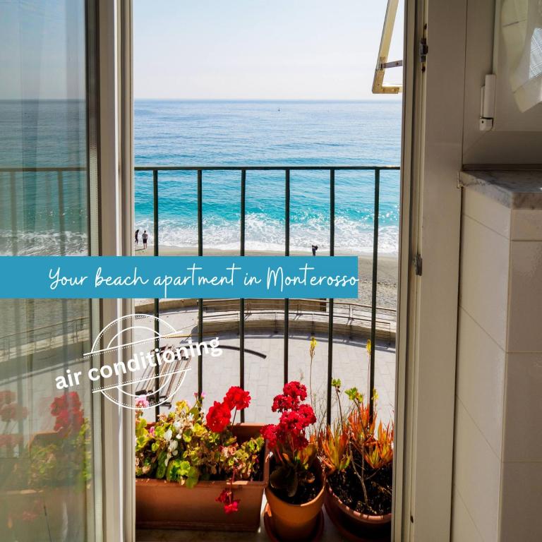 a view of the beach from a balcony with flowers at Giaella Sea View Apartment in Monterosso al Mare
