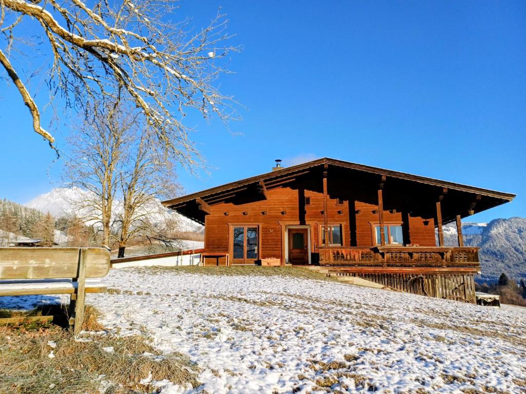 een blokhut in de sneeuw met een bank bij Ferienwohnung Schösserhof in Reith bei Kitzbühel