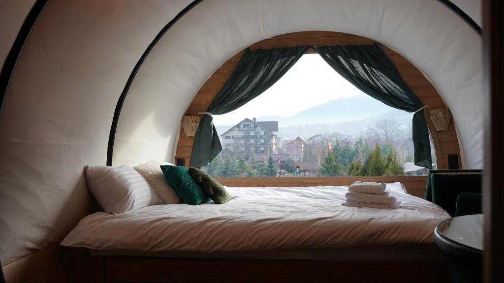 un letto in una camera con una grande finestra di Nomad by Hora cu Brazi a Zărneşti