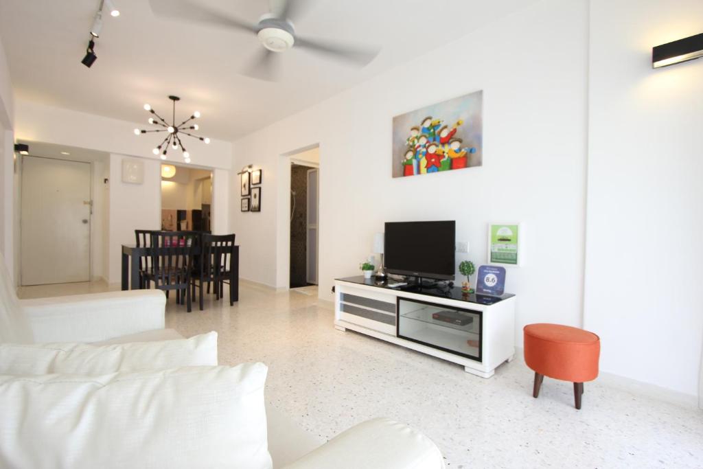uma sala de estar com um sofá branco e uma televisão em Cosy Stay Melaka em Malaca