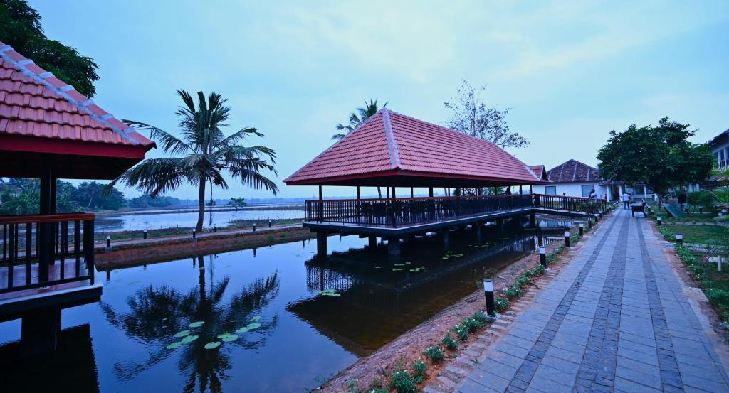 a building with a pier next to a body of water at Vedic Village Retreat Alleppey in Alleppey