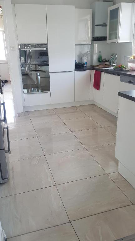 een keuken met witte kasten en een tegelvloer bij Chambre n 2 in Schiltigheim