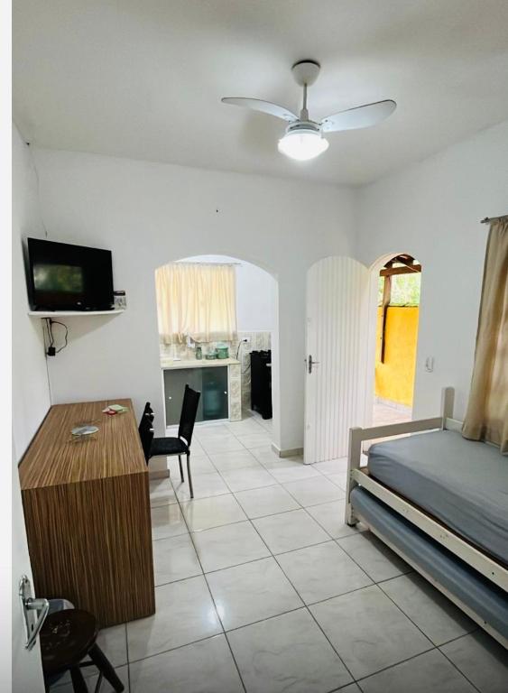 a bedroom with a bed and a table and a tv at Chalés Boraceia Duda in Boracéia