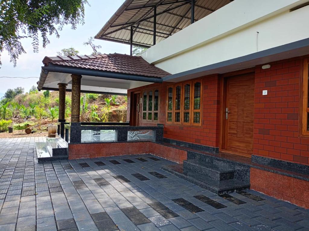 ein rotes Backsteingebäude mit einem Pavillon auf einer Terrasse in der Unterkunft Valley De Hills Farm Villa in Attappādi