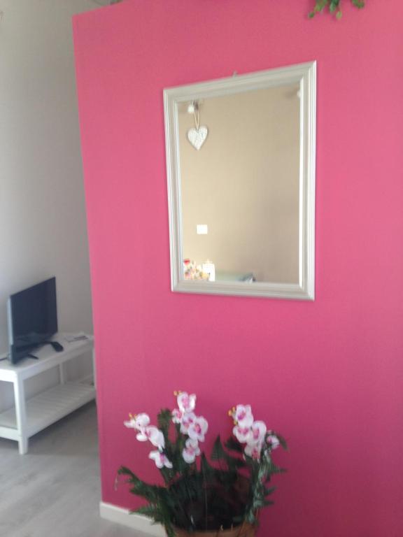 un mur rose avec un miroir et un vase de fleurs dans l'établissement appartamento giorgia, à Schio