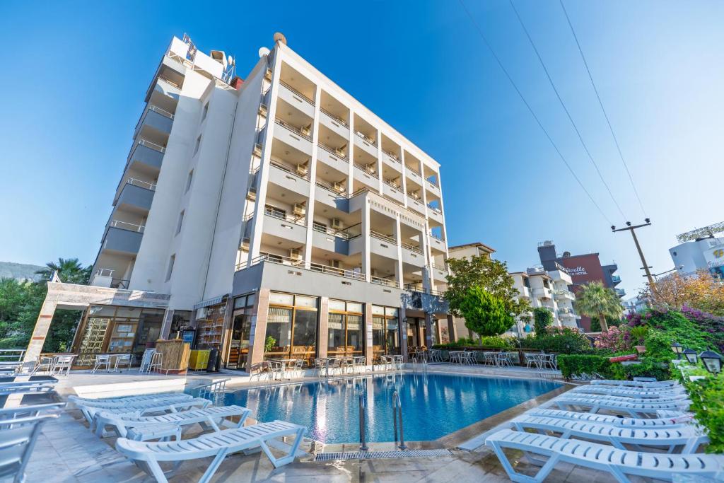 a hotel with a swimming pool and chairs and a building at Çidihan HOTEL in Kuşadası