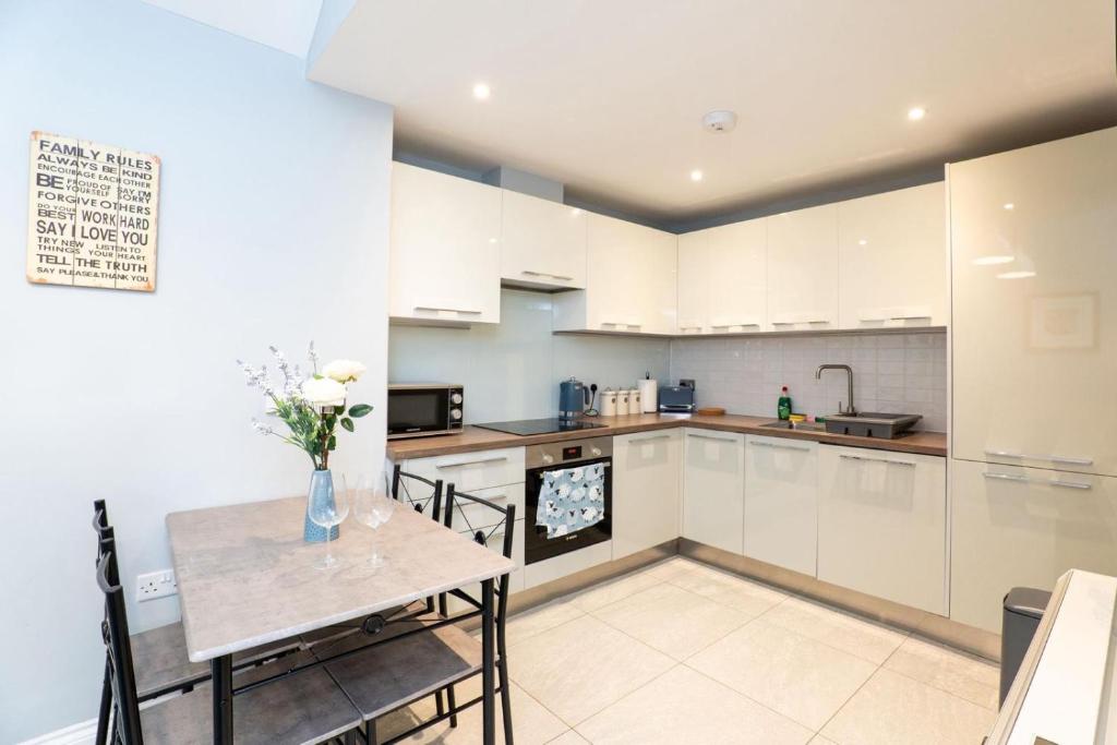 eine Küche mit weißen Schränken und einem Tisch und Stühlen in der Unterkunft Nr 8 - Modern 2 Bed Flat - WiFi - Town Centre - Parking in Bedford