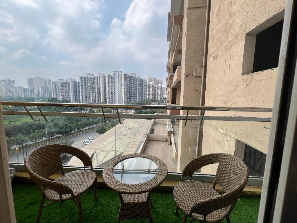 drie stoelen en een tafel op een balkon met uitzicht bij Eden Suite in Noida
