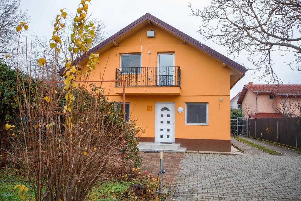a yellow house with a balcony on a driveway at Casa Andrea in Otopeni