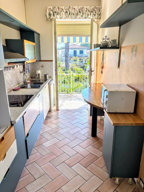 a kitchen with a counter and a table in it at Il Sole in Terrazza - A due Passi dal Mare - Private Garden and Parking in Cinquale