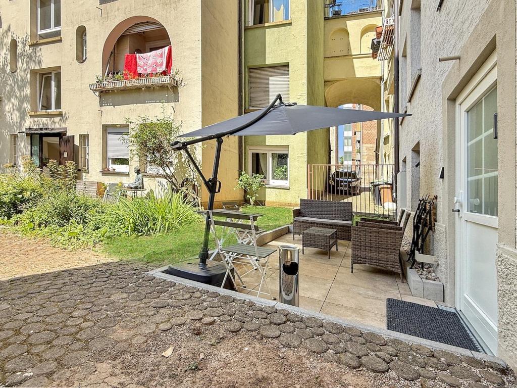 a patio with an umbrella and a table and chairs at Stgt Gartenwohnung mit Patio - 4 Personen in Stuttgart