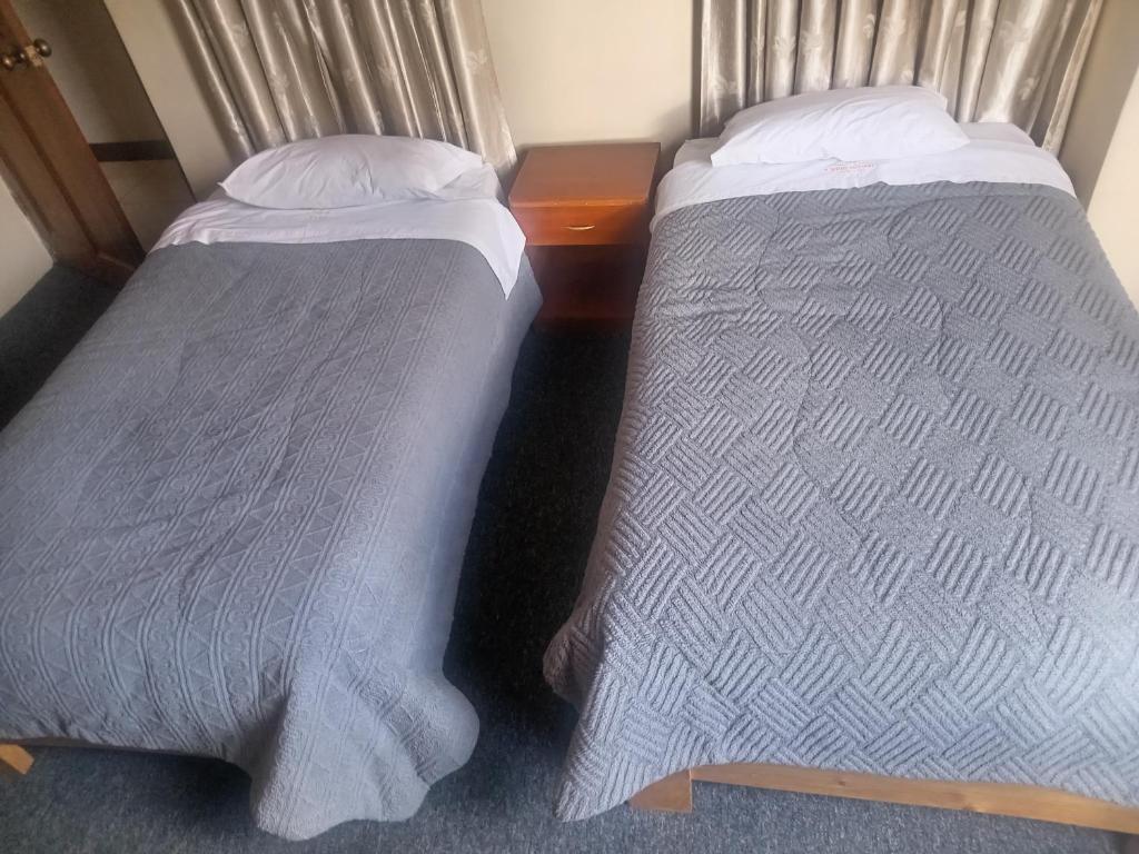 twee bedden naast elkaar in een kamer bij Pirqainn in Puno