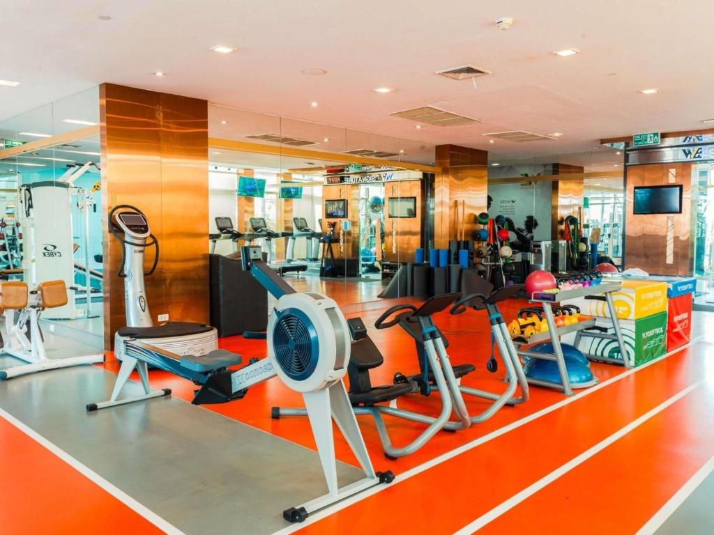 A bright cardio gym includes treadmills, a rowing machine, bikes, and resistance equipment.