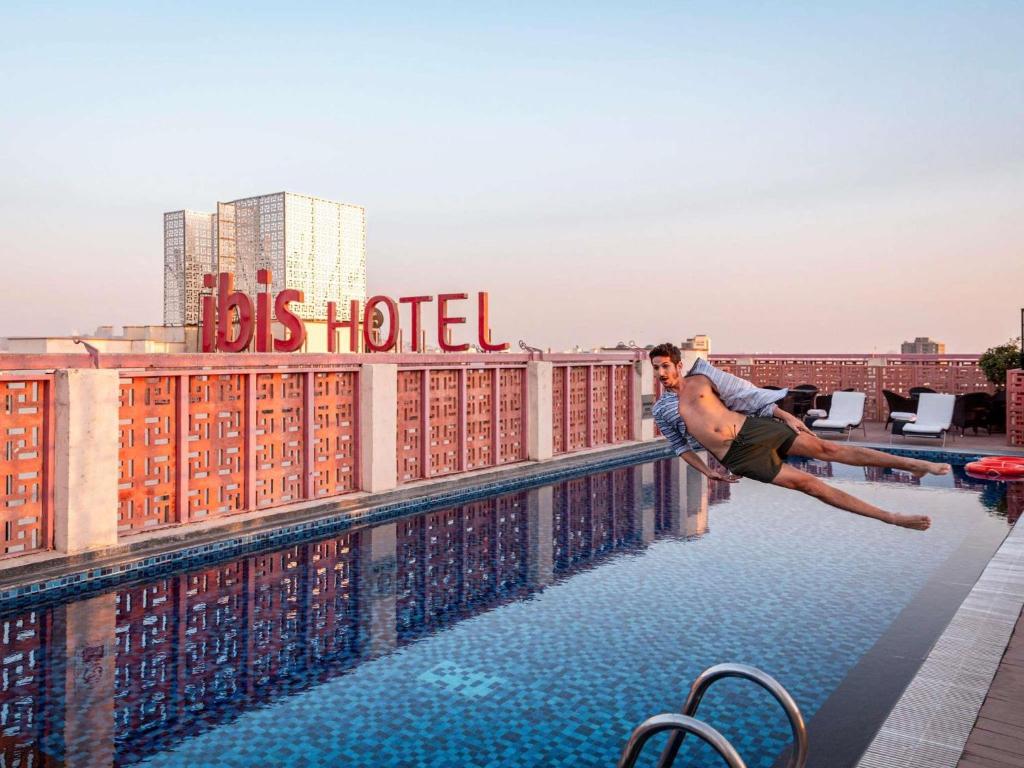 Ein Mann springt in einen Swimmingpool auf einem Gebäudedach in der Unterkunft ibis Jaipur City Centre - An Accor Brand in Jaipur
