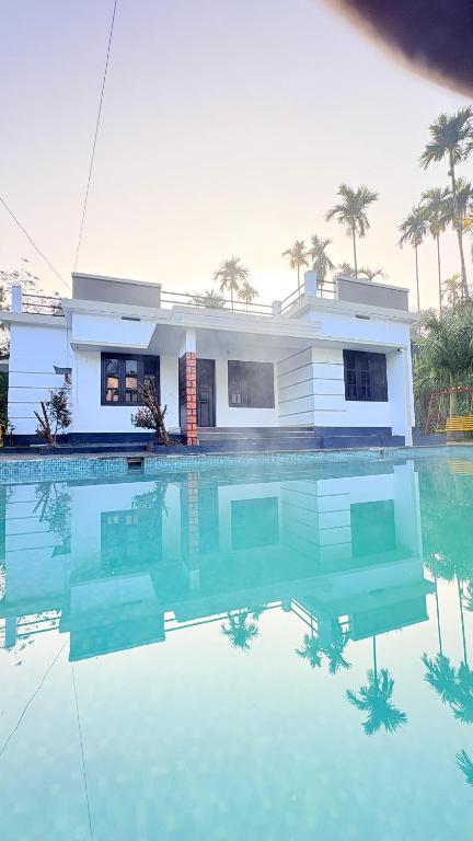 una casa con piscina di fronte a una casa di Grand Glorious Resort a Padinjarathara