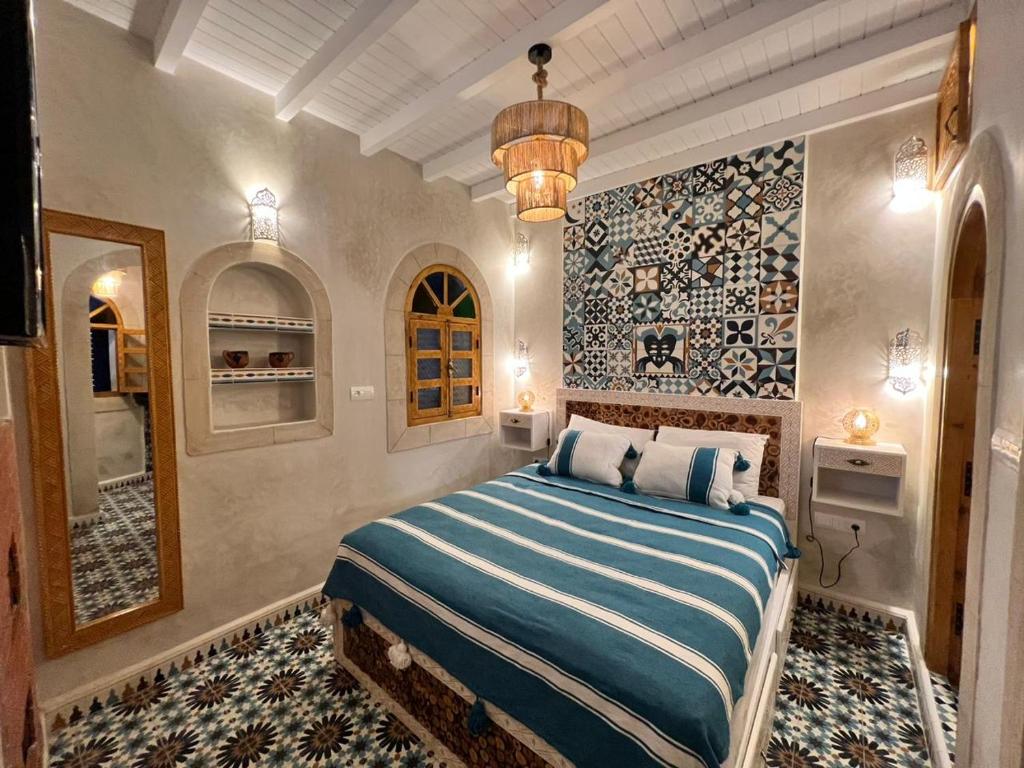 een slaapkamer met een bed in een kamer met een muur bij Riad dar el hania in Essaouira