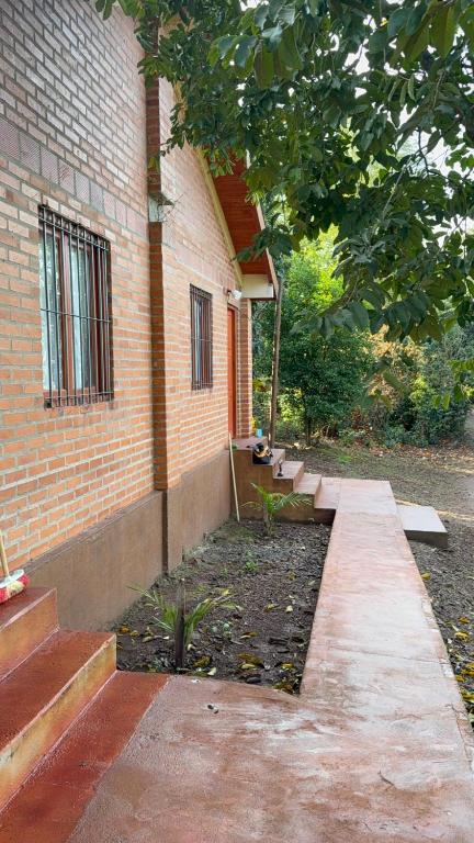 a brick building with steps leading into a yard at Cabañas la flor in Puerto Piray