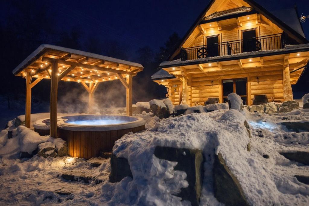una baita di tronchi con vasca idromassaggio nella neve di Góralska Chatka jacuzzi i sauna a Kościelisko