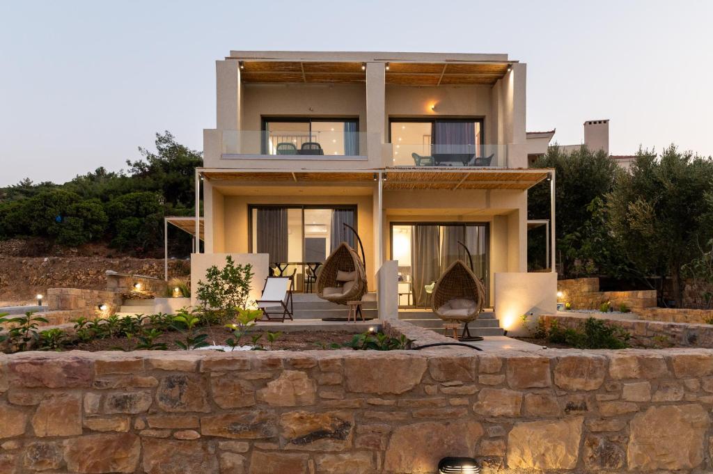 una casa su una collina con un muro di pietra di Enalis Studios & Apartments a Karfás