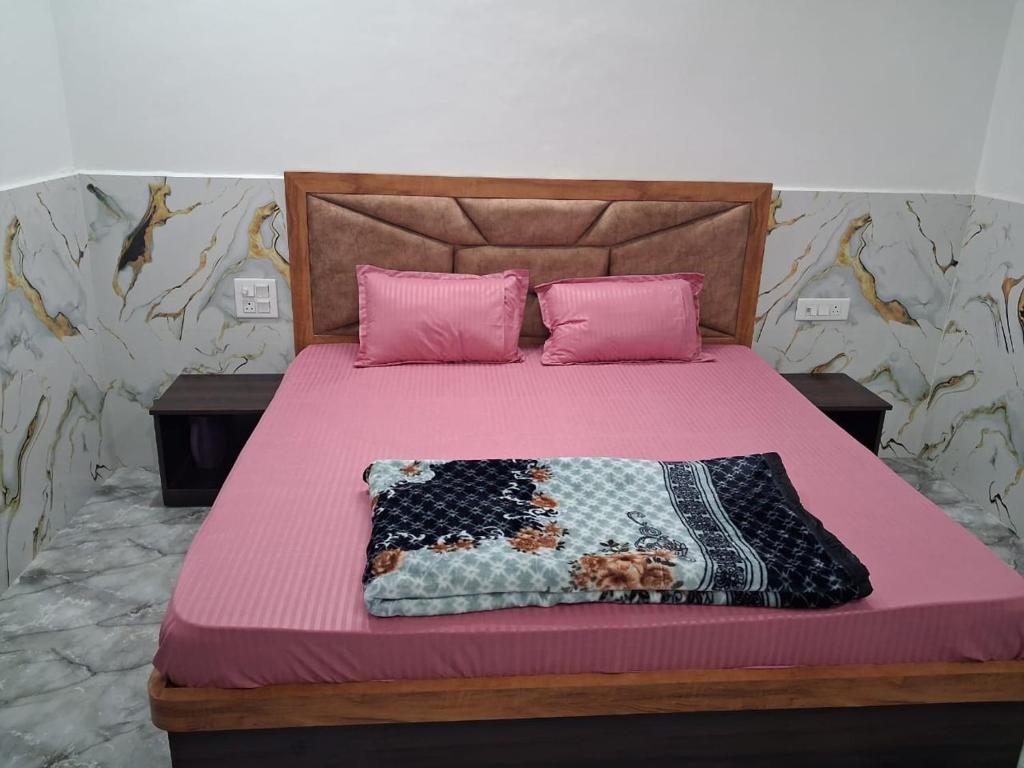 Schlafzimmer mit einem Bett mit rosa Bettwäsche und rosa Kissen in der Unterkunft Prabhu Kripa Dham Guest House in Jāmb