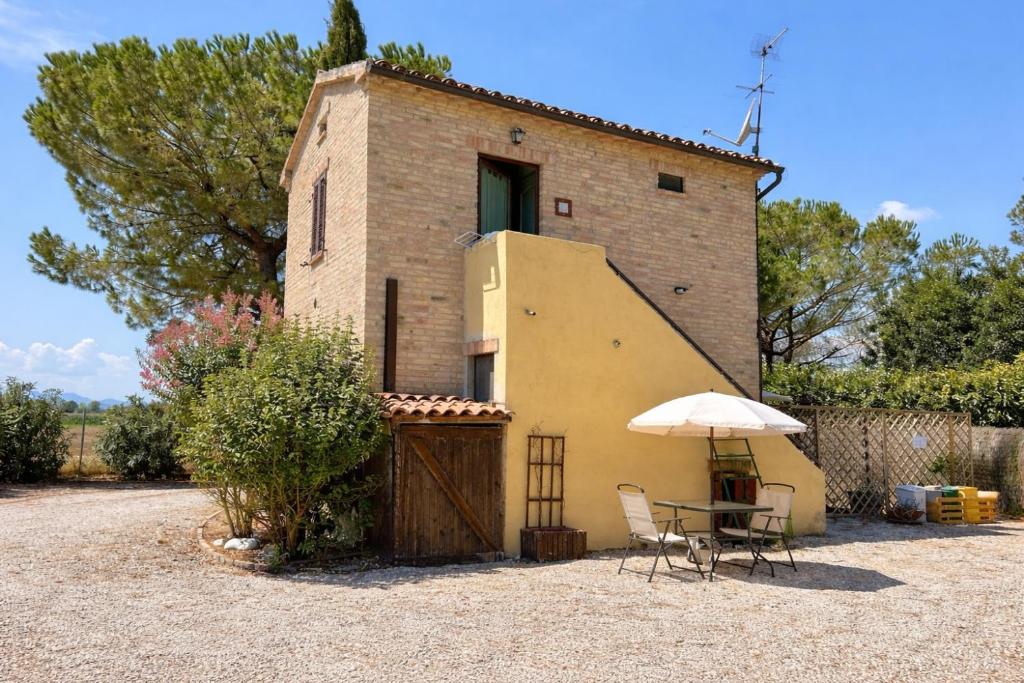 een gebouw met een tafel en een paraplu ervoor bij fattoria Coppetella Cemani in Molino dʼAgugliano