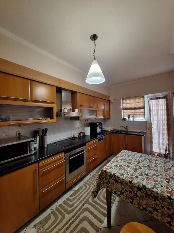 een keuken met houten kasten en een tafel. bij 4youAPARTMENT in Tríkala