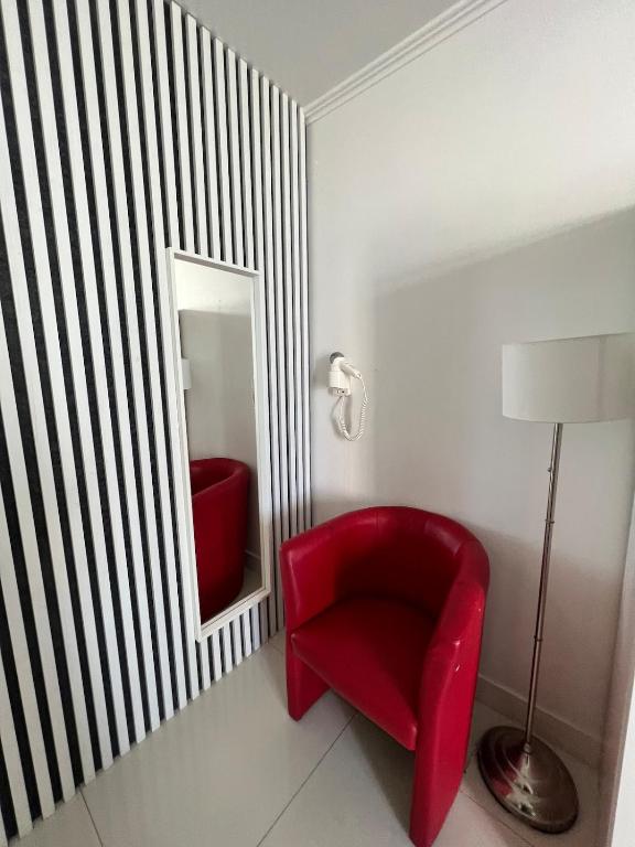 una sedia rossa in una stanza con specchio di Panoramic Balcony Apartment a Varsavia