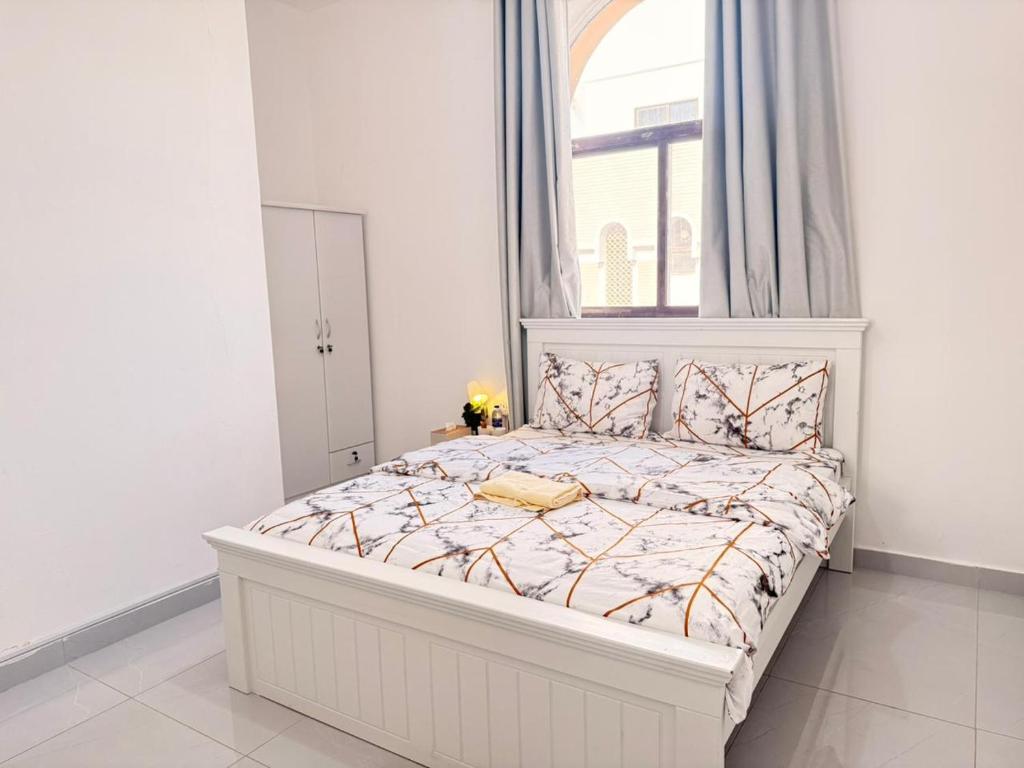 un letto bianco in una camera bianca con finestra di Flora Residence a Abu Dhabi