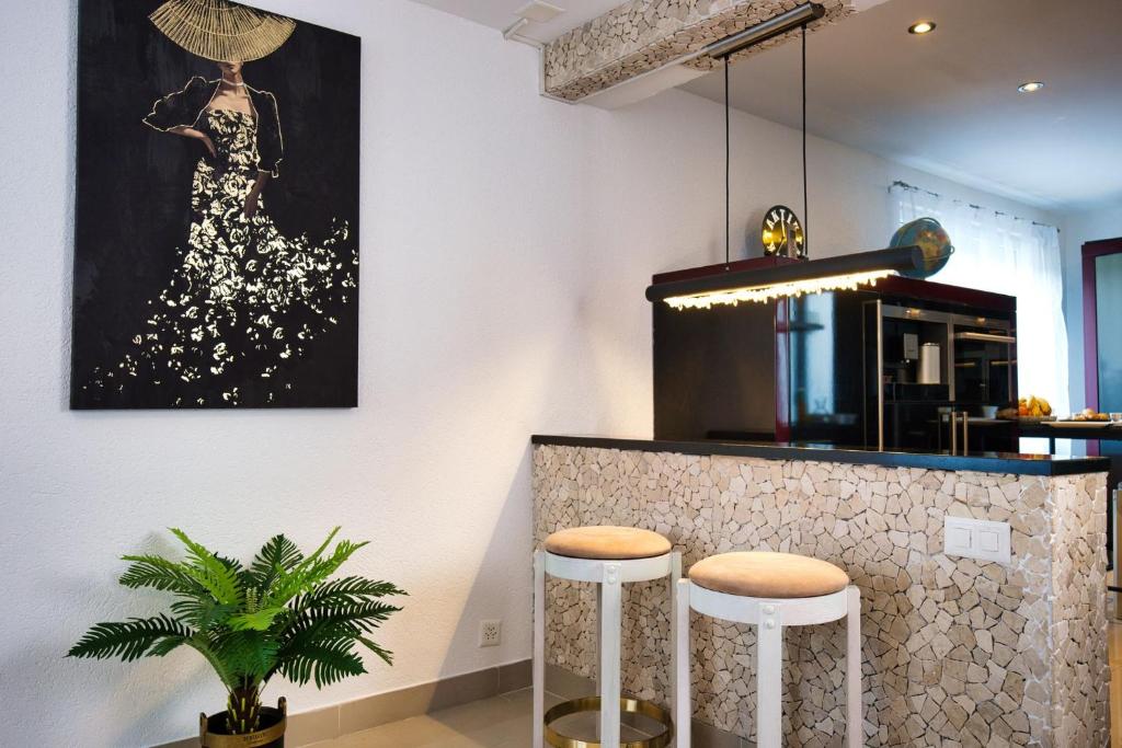 une cuisine avec un bar avec des tabourets et un tableau dans l'établissement Modern Station Apartment Mhlin, à Möhlin
