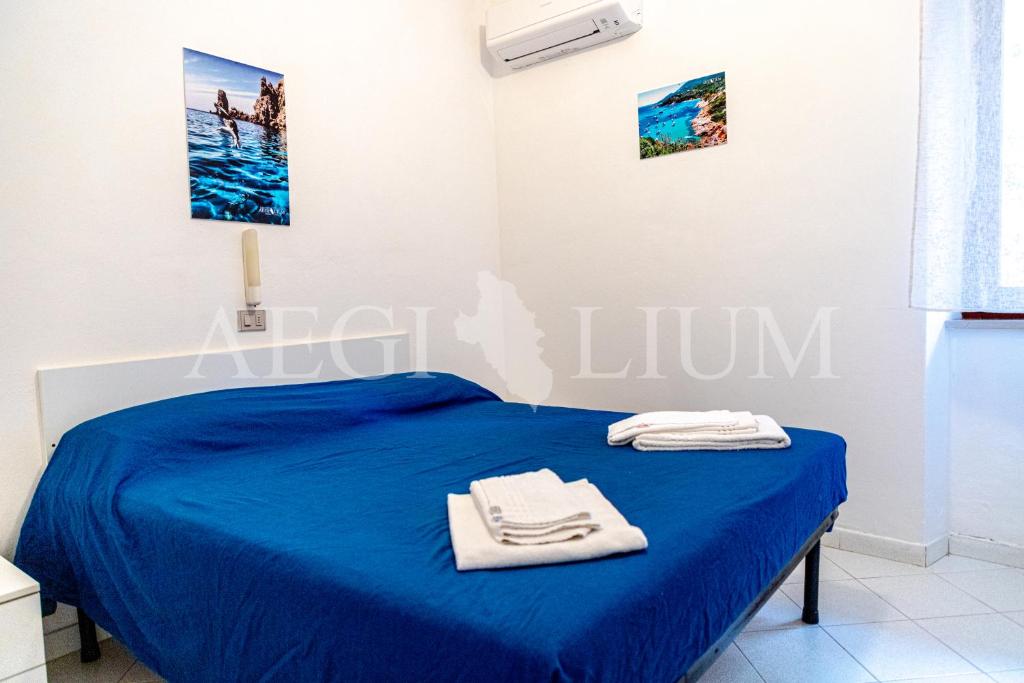 een slaapkamer met een blauw bed met handdoeken erop bij Carla 1 in Campese