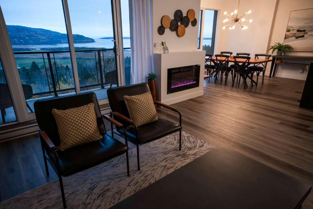 een woonkamer met twee stoelen en een open haard bij Luxury Coffee Bean Condo - Pool & Stunning View in Baie-Saint-Paul