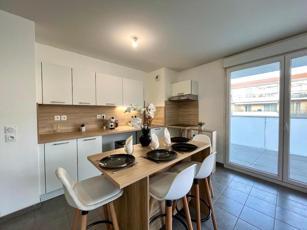 eine Küche mit Tisch und Stühlen in einem Zimmer in der Unterkunft Le Casual avec parking - 5 pers - Proche Gare Vénissieux - à 15 min de Lyon in Vénissieux